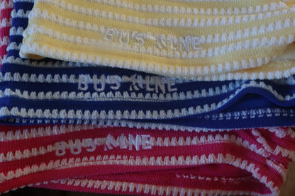 Four pairs of striped socks in red, blue, and yellow with 'BUSBY' branding.